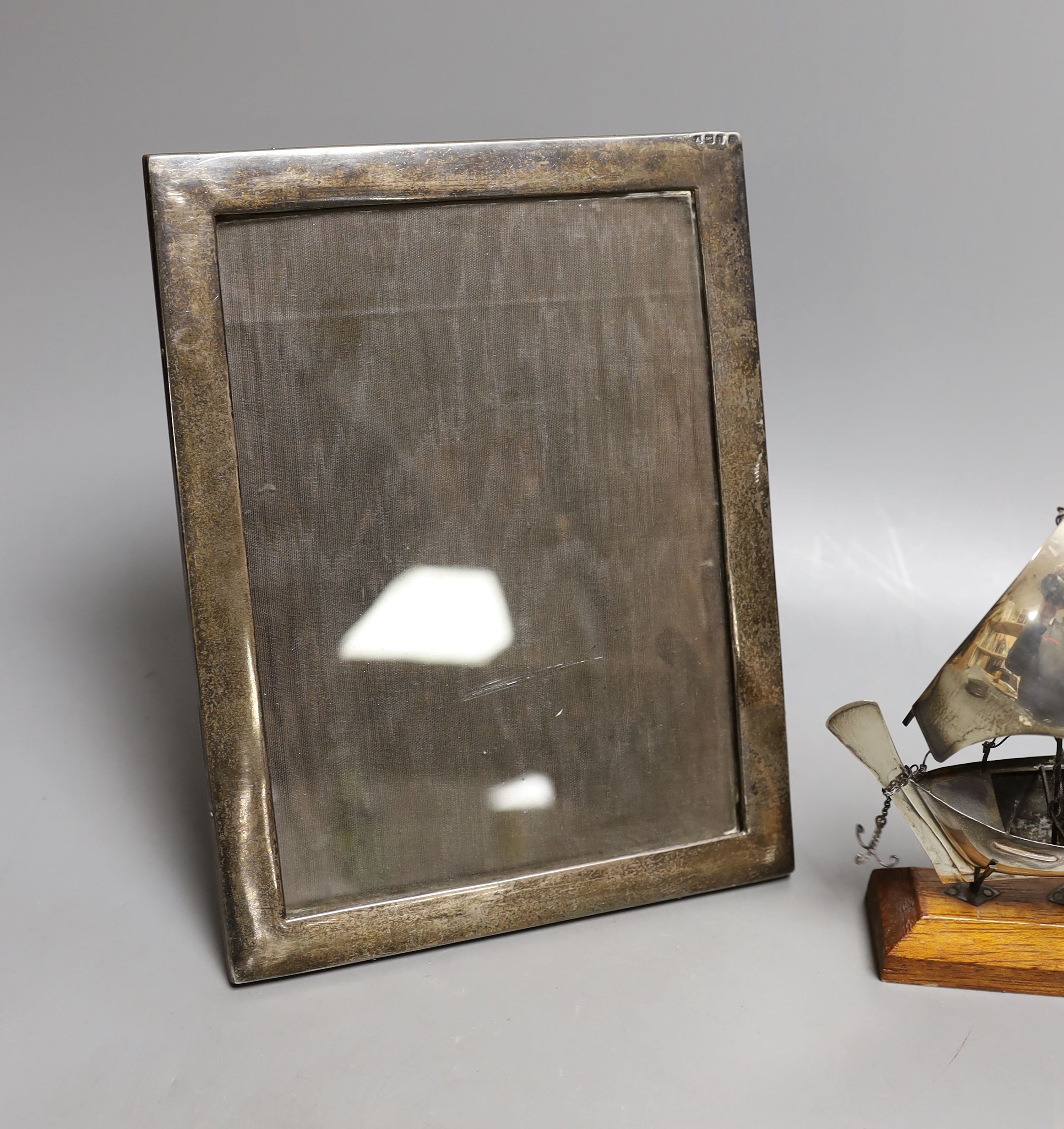 A George V silver mounted rectangular photograph frame, 24.2cm, a 1930's silver trinket box and a miniature white metal model of a sail boat, on wooden stand.